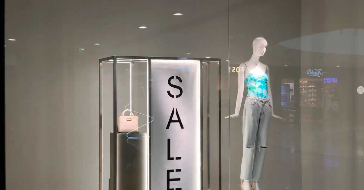 Vitrine élégante avec panneau de vente et mannequin à la mode vêtu d'une tenue tendance.