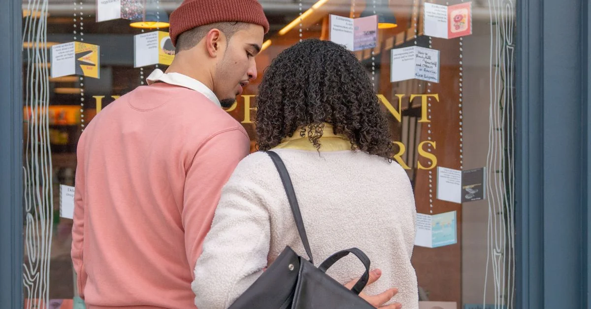Un couple s'enlace tendrement tout en faisant du lèche-vitrine dans une librairie indépendante.